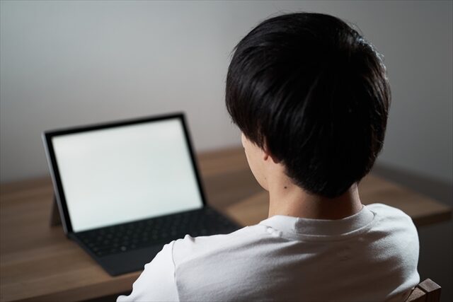 夜に自宅でパソコンに向かう父親の様子